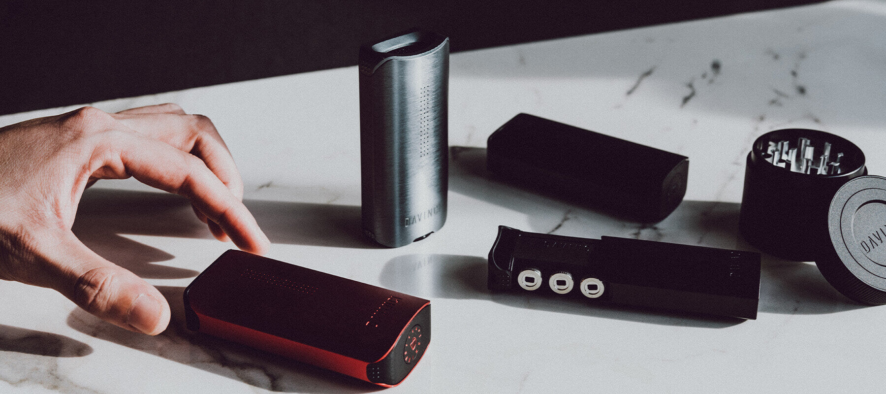 Close-up of black and red Davinci heating devices and accessories on a marble counter.